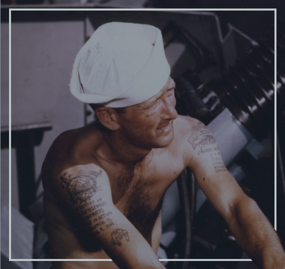 A sailor with an arm tattoo operates a cannon.